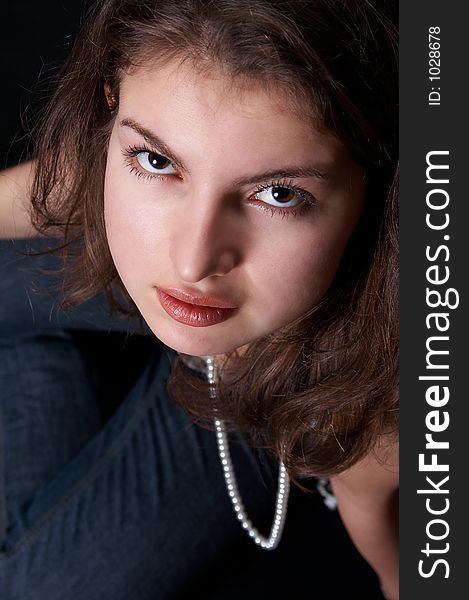 Girl with pearls and jeans looking up at the photographer. Girl with pearls and jeans looking up at the photographer