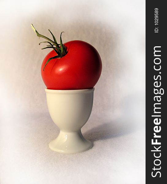 Tomato set on top of an egg cup, depicting you can have a tomato for breakfast as well as eggs. Tomato set on top of an egg cup, depicting you can have a tomato for breakfast as well as eggs.