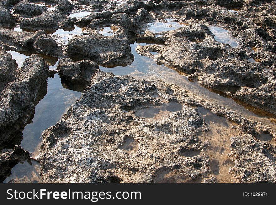 Rocky scenic from a rocky seashore. Sea water corroded the rock which form small holes which are filled with sea water. Rocky scenic from a rocky seashore. Sea water corroded the rock which form small holes which are filled with sea water