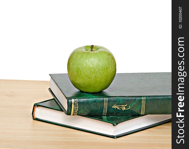 Green apple on books on desk
