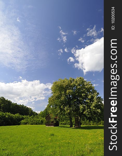 Green meadow with a wooden chapel under a picturesque sky. Green meadow with a wooden chapel under a picturesque sky