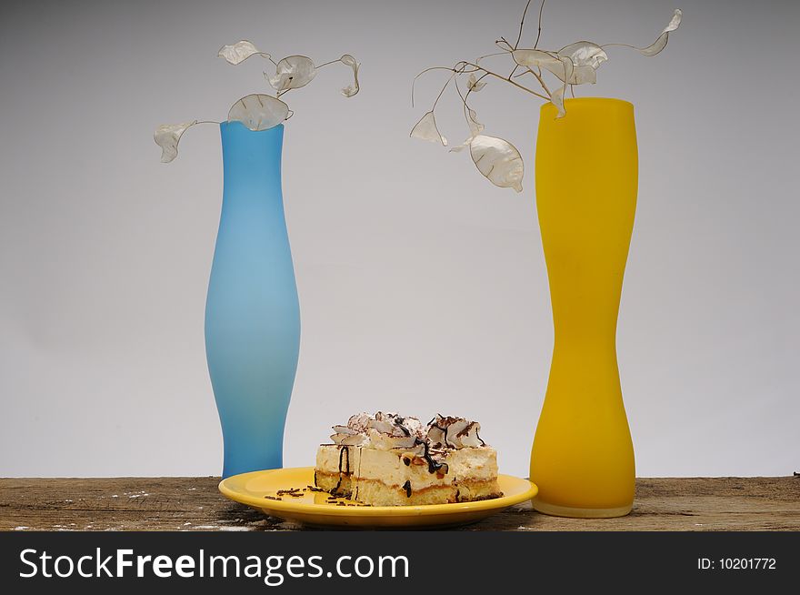 Close up with cakes  on yellow plate and two vases