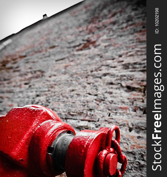 A red hydrant against high brick wall.