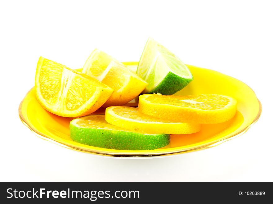 Assortment of lemon, lime and orange segments on a fancy yellow plate with a white background. Assortment of lemon, lime and orange segments on a fancy yellow plate with a white background