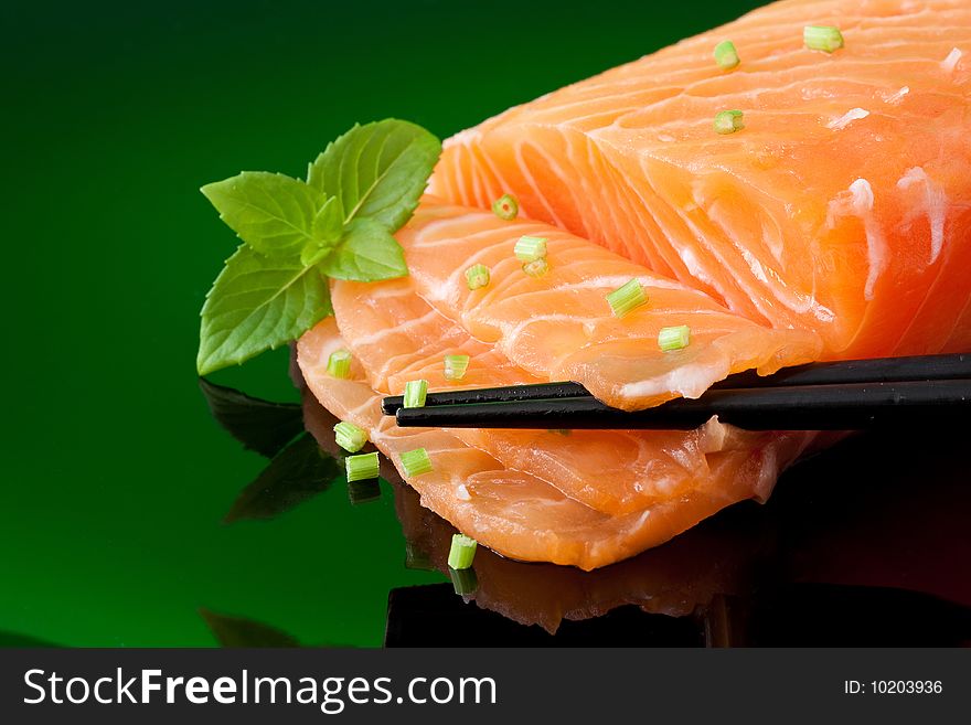 A piece of fresh salmon with basil leaves and chopstick