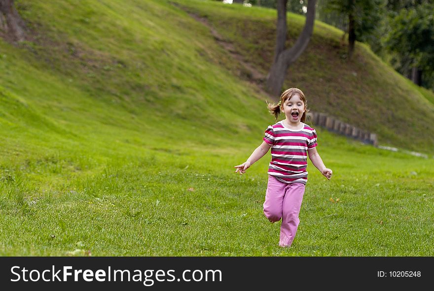 Little girl running on the grass in the park. Little girl running on the grass in the park