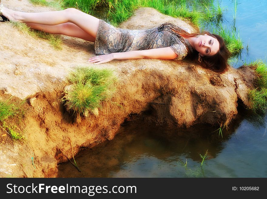 Beautiful sexual woman lays ashore near water. Beautiful sexual woman lays ashore near water