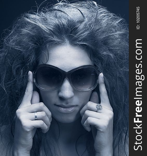 Portrait of young woman in sunglasses on the dark background