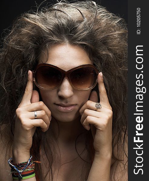 Portrait of young woman in sunglasses on the dark background