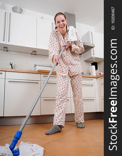 Woman in pajamas cleaning the kitchen with a mop