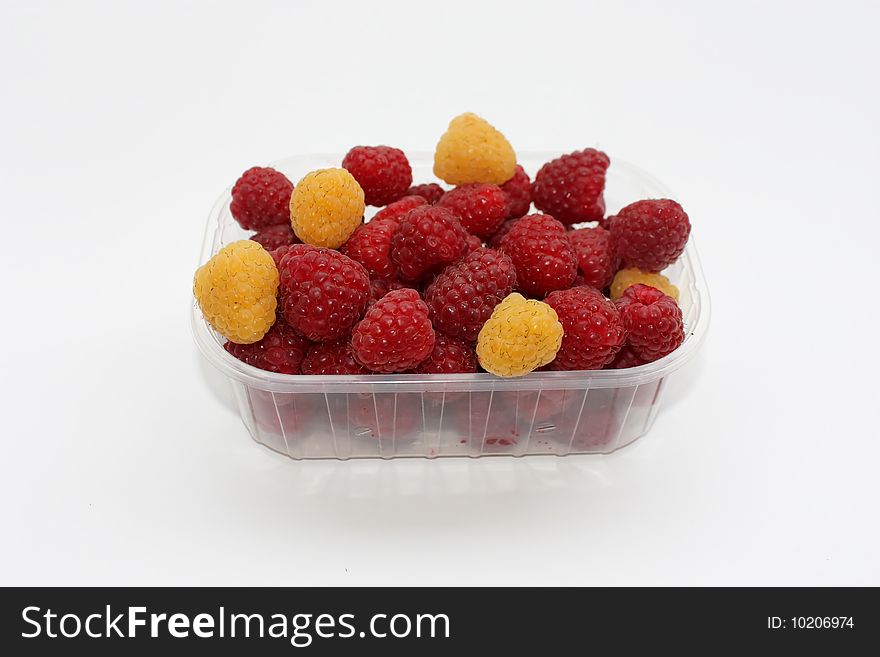 Fresh raspberries with some yellow berries in a container, isolated
