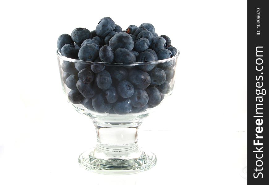 A glass bowl of fresh blueberries on a white background. A glass bowl of fresh blueberries on a white background