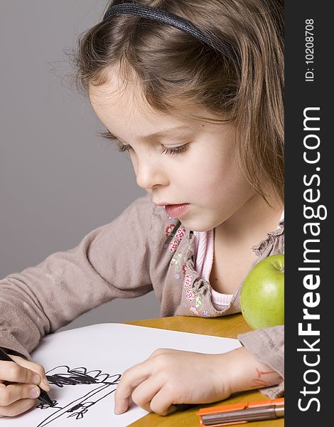 Little girl drawing a picture with a green apple