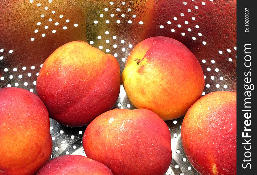 Washed nectarines covered with droplets in strainer