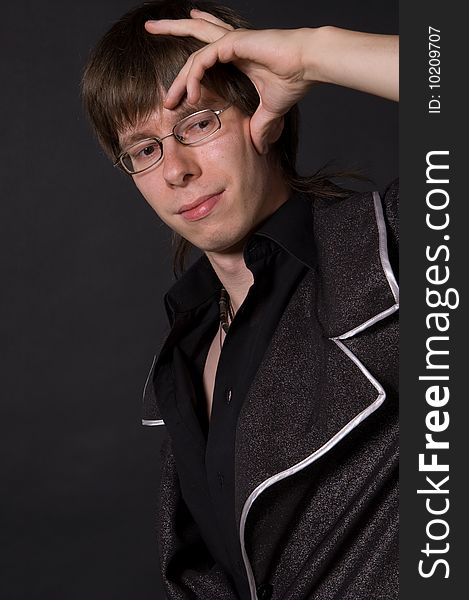 Portrait of young thinking man with glasses, black background