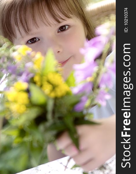 Little girl with the big bouquet of summer flowers