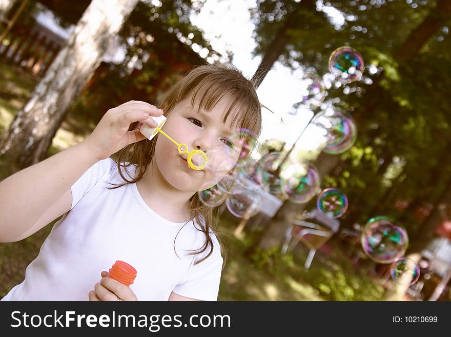 Little gir concentrated on blowing soap bubbles,  bubbles unfocused