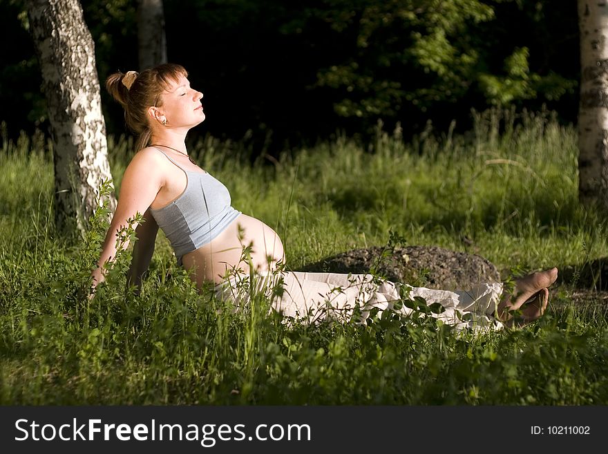 Pregnant woman sitting on grass and relax. Pregnant woman sitting on grass and relax.