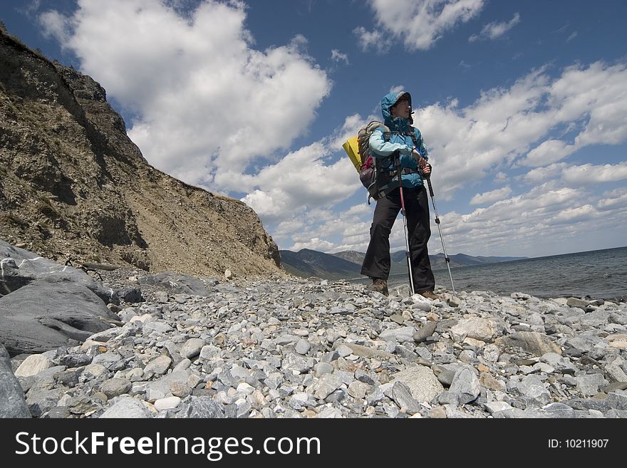 Woman backpacker goes on a coast. Lake Baikal, Eastern Siberia