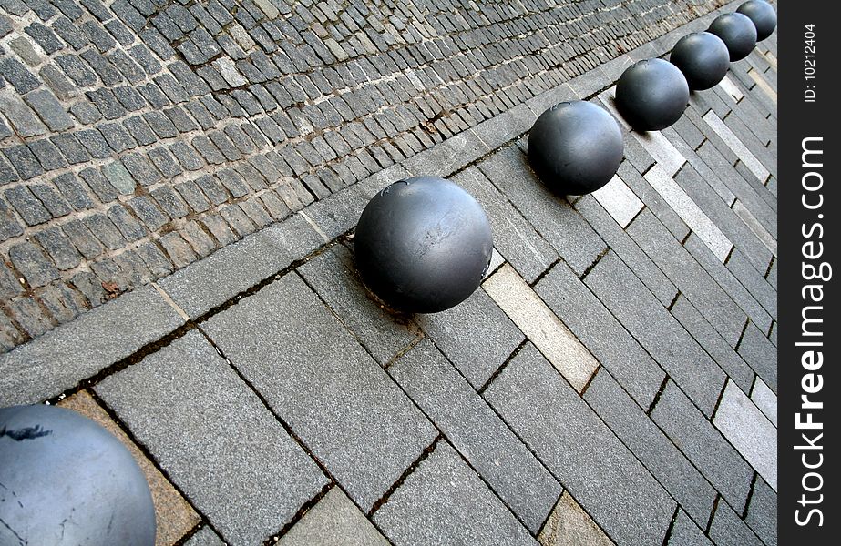 Metal balls on sidewalk aligned diagonally. Metal balls on sidewalk aligned diagonally