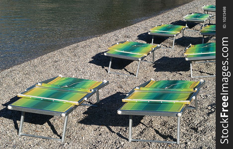 Colored sunbeds on pebble beach by Lake Garda, Italy