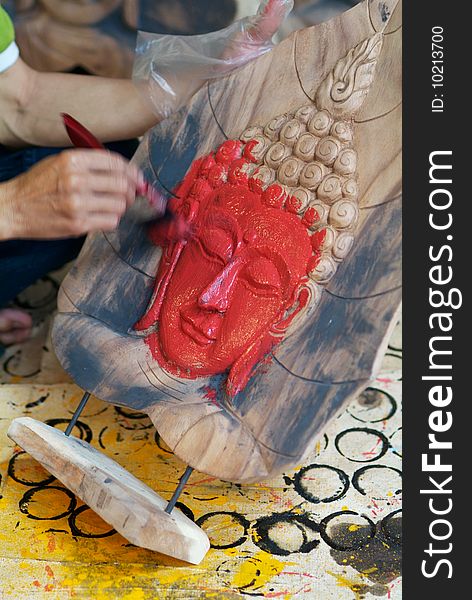 Hand painting the face of a Buddha image with red paint. Motion blur on the painting hand. Hand painting the face of a Buddha image with red paint. Motion blur on the painting hand.