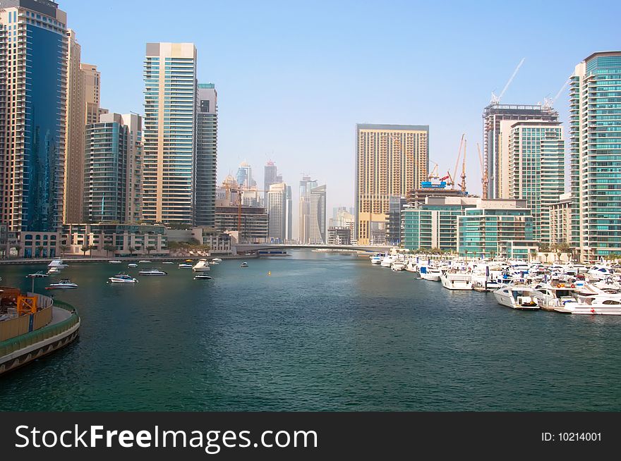 Several boats and yachts berthed in the Dubai Marina with luxury apartments in the background. Several boats and yachts berthed in the Dubai Marina with luxury apartments in the background