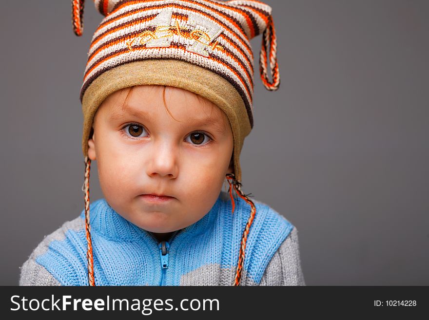 Closeup portrait of a little boy in a nice striped cap, serious thoughtful look. Closeup portrait of a little boy in a nice striped cap, serious thoughtful look