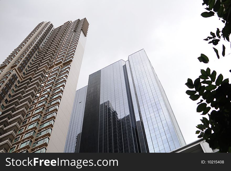 Tall buildings in street. A residential building is just beside a commercial build. They are face to face and almost can shake hands with each other.