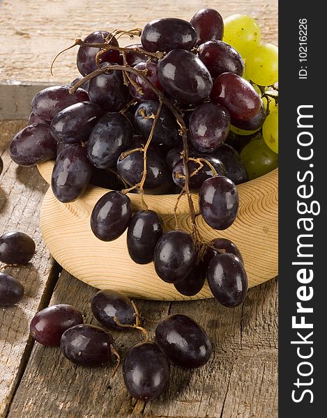 grapes on a wooden bowl on an old table