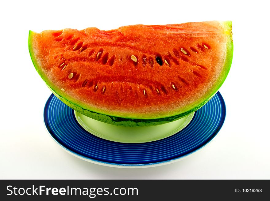 Slice of watermelon with green skin and red melon with seeds on a blue plate with a white background