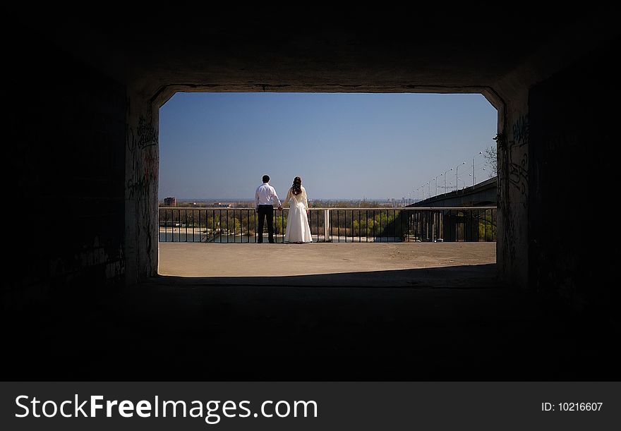 The groom holds the bride for a hand. A view from a dark tunnel. The groom holds the bride for a hand. A view from a dark tunnel