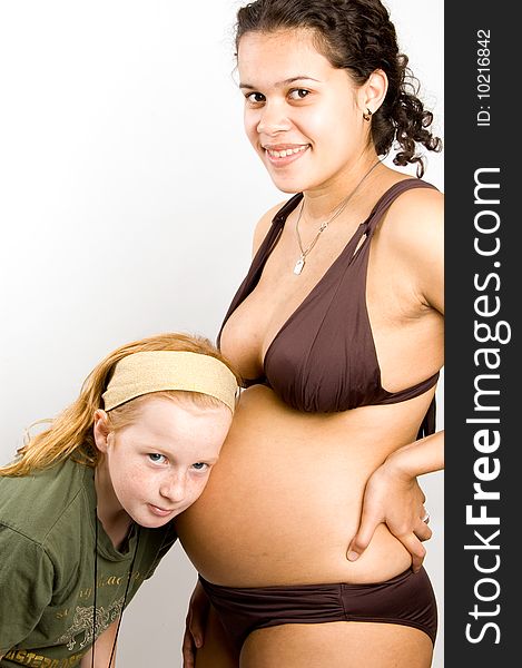 Little girl is listening to the baby inside the belly on white