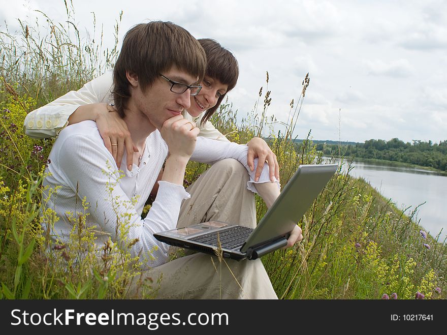 The man and women with laptop on green grass