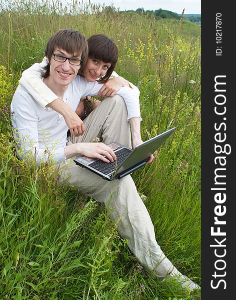 The man and women with laptop on green grass