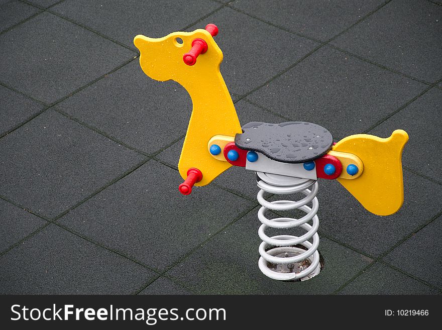 Yellow seesaw in rain shaped like animal on gray background