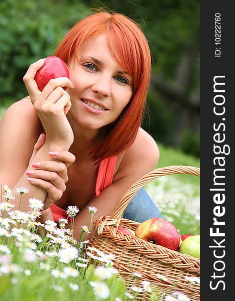 Beautiful girl with a basket of apples on a meadow