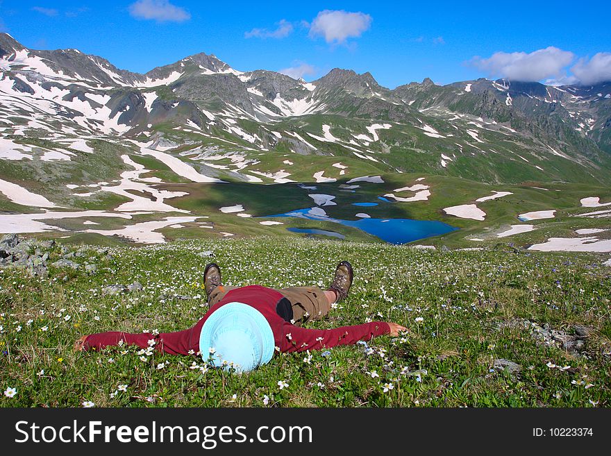 Hiker lies on meadow in mountains