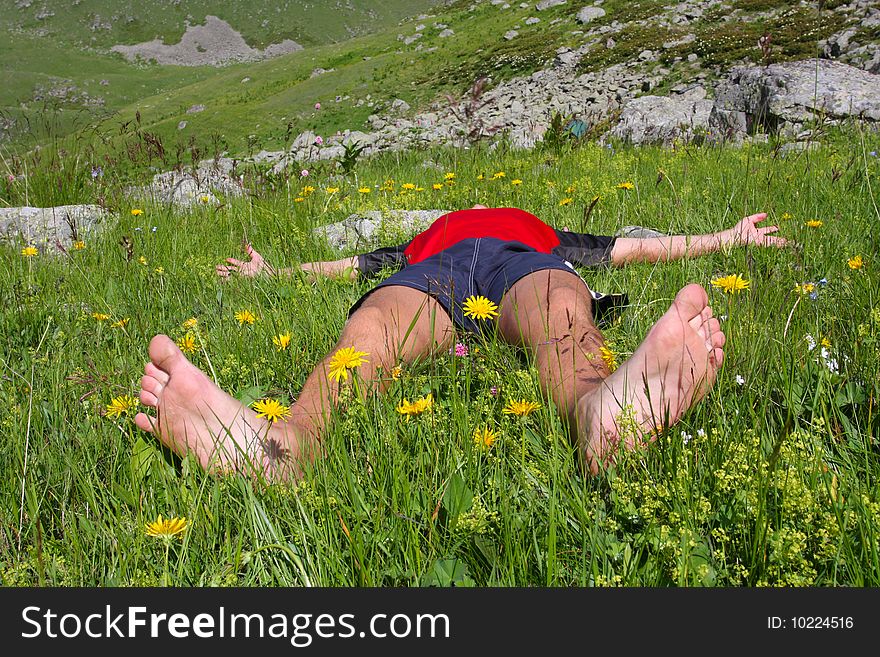 Hiker lies on meadow in mountains