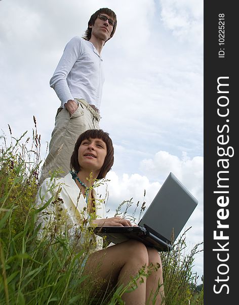 The man and women with laptop on green grass