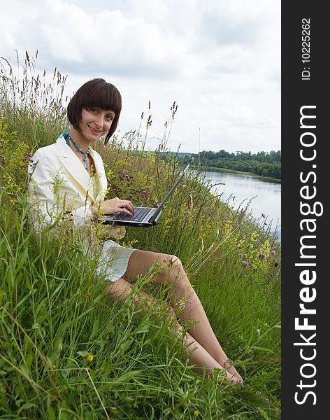 The woman with laptop on green grass