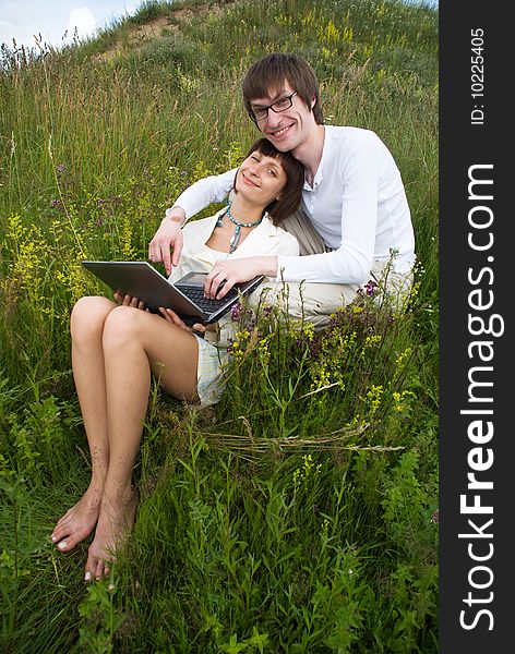 The man and women with laptop on green grass