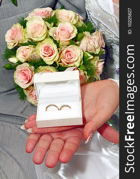 Two wedding rings in white box and bouquet for fiance and fiancee