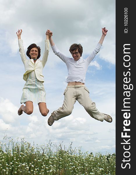 Jumping girl and boy on green meadow