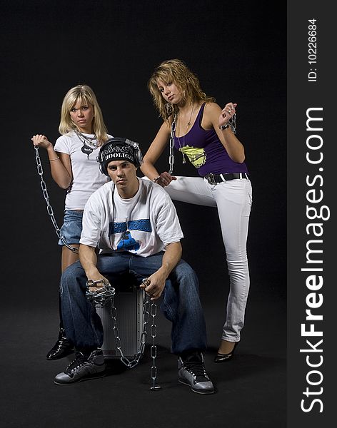 Young DJ/rapper with two teen girls with chains isolated on black background. Young DJ/rapper with two teen girls with chains isolated on black background