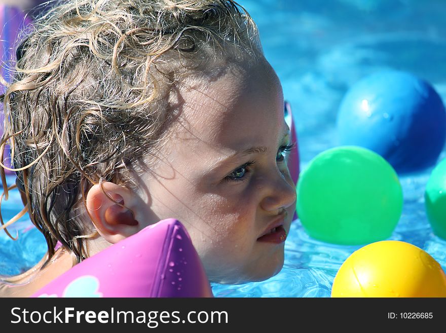 A small child swimming in a pool full of colorful balls. A small child swimming in a pool full of colorful balls