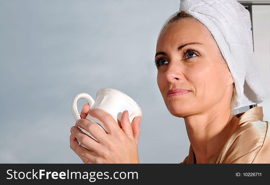 Woman in bathrobe sitting at window drinking coffee. Woman in bathrobe sitting at window drinking coffee