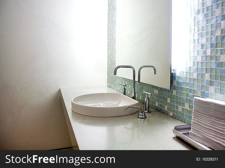 Detail of a bathroom at the clinic, showing a mirror, sink and tiles