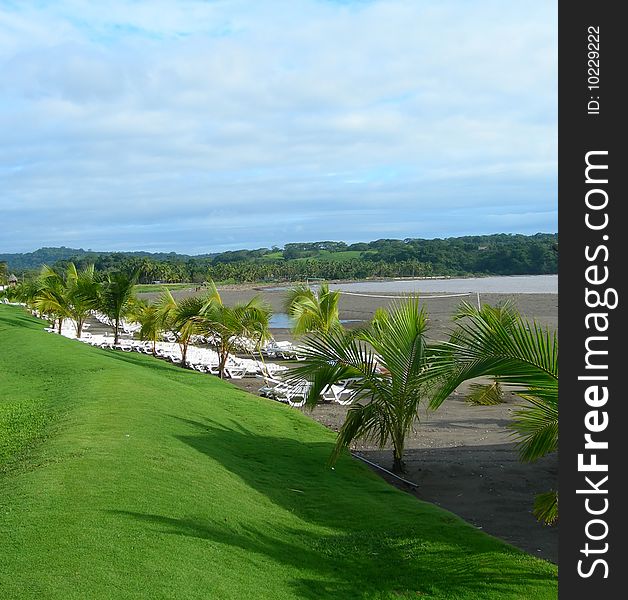 Tropical volcanic dark sand beach and grassy knoll at resort in Costa Rica