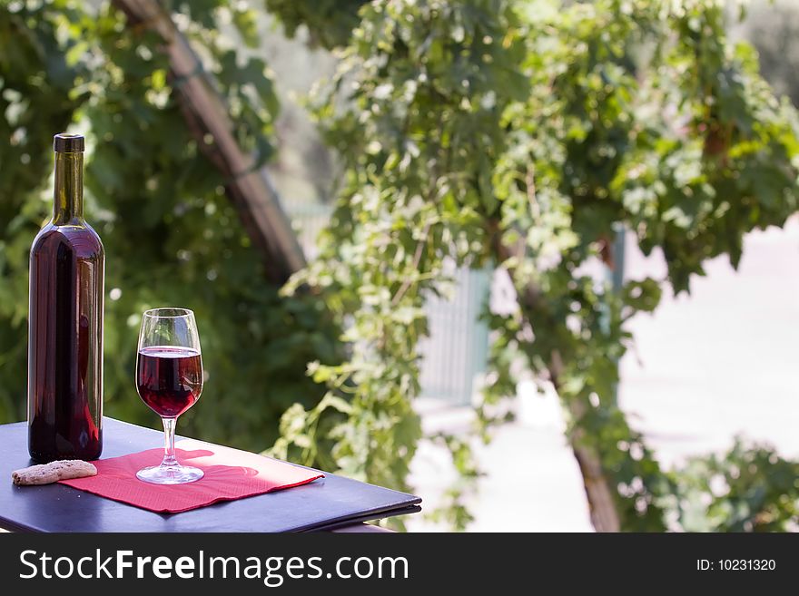 A glass and a bottle of wine on a table ready to be drunk. A glass and a bottle of wine on a table ready to be drunk